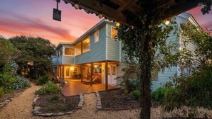 A two-story house with a covered patio, a stone pathway, and a garden area. - Secret Garden Stay - Team Joseph Ellen (Fernandina Beach)