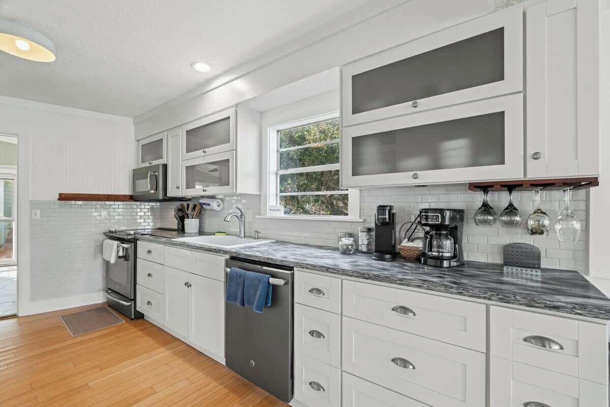 A modern kitchen with white cabinetry, a marble countertop, and a built-in oven.