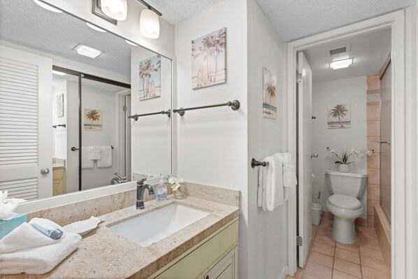 A bathroom with a sink, mirror, towel rack, toilet, and shower.