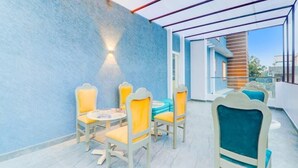 A balcony with a blue wall, yellow chairs, and a table. - The Grand Homes (Lucknow)
