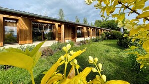A modern wooden building with large windows and a well-maintained garden.