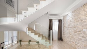 A modern interior with a glass staircase, stone walls, and a wooden floor. - Villa Gambin (100121-K1) - Kastelir (Kastelir)