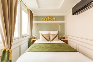 A neatly arranged bedroom with a bed, curtains, a nightstand, a wall-mounted air conditioner, and a decorative wall piece. - Merveil Luxury Suite - Eiffel Fremicourt (Paris)