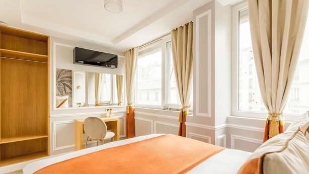 Quarto de hotel com cama, escrivaninha, cadeira e guarda-roupa.