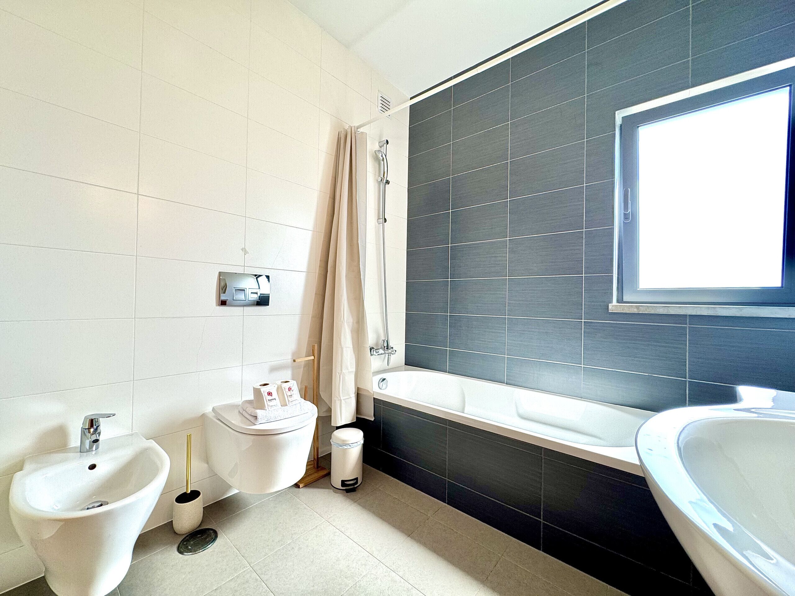 Een moderne badkamer met een bidet, toilet en bad.