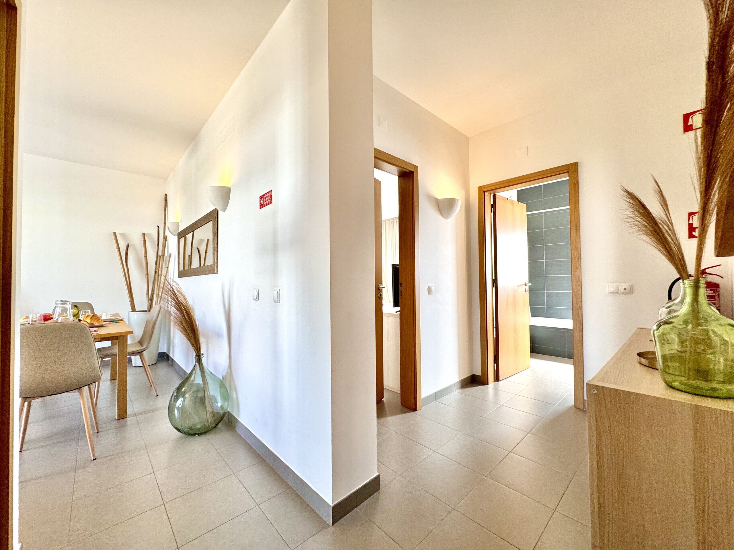 A hotel corridor with a dining area, a reception desk, and a bathroom visible through an open door.