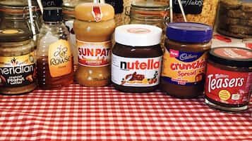 A variety of jars and containers of spreads and condiments on a checkered tablecloth.