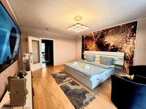 A modern bedroom with a bed, a large mirror, a wall-mounted light, and a decorative plant. - 2-Zim, 4Pers,neben Einkaufszentrum, Parkplatz in Mülheim an der Ruhr (Mülheim an der Ruhr)