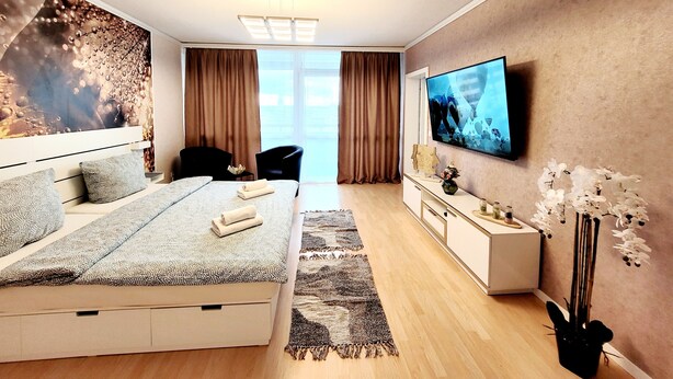 Une chambre d’hôtel moderne dotée d’un grand lit, d’une télévision à écran plat, d’un bureau et offrant une vue sur la ville grâce à de grandes fenêtres.