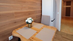 Une cuisine moderne avec des meubles en bois, un réfrigérateur blanc et une petite table agrémentée d’une plante en pot.