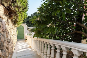 A stone pathway leading to a green gate, surrounded by lush greenery and a white balustrade. - Villa 'Miramar' with Sea Views, Wi-Fi and Air Conditioning (Rincón de la victoria)