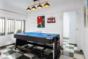 Une table de billard avec un tapis de jeu bleu, une boule blanche et une boule rouge, et un support contenant un jeu de billes.