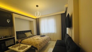 Een hotelkamer met een bed, een bank, een tafeltje, een televisie en een kitchenette.