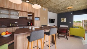 A modern kitchen with wooden cabinets, a central island with bar stools, a coffee machine, and a TV mounted on the wall. - Villa 115 (100401-K1) - Visnjan (Porec) (Visnjan (Porec))