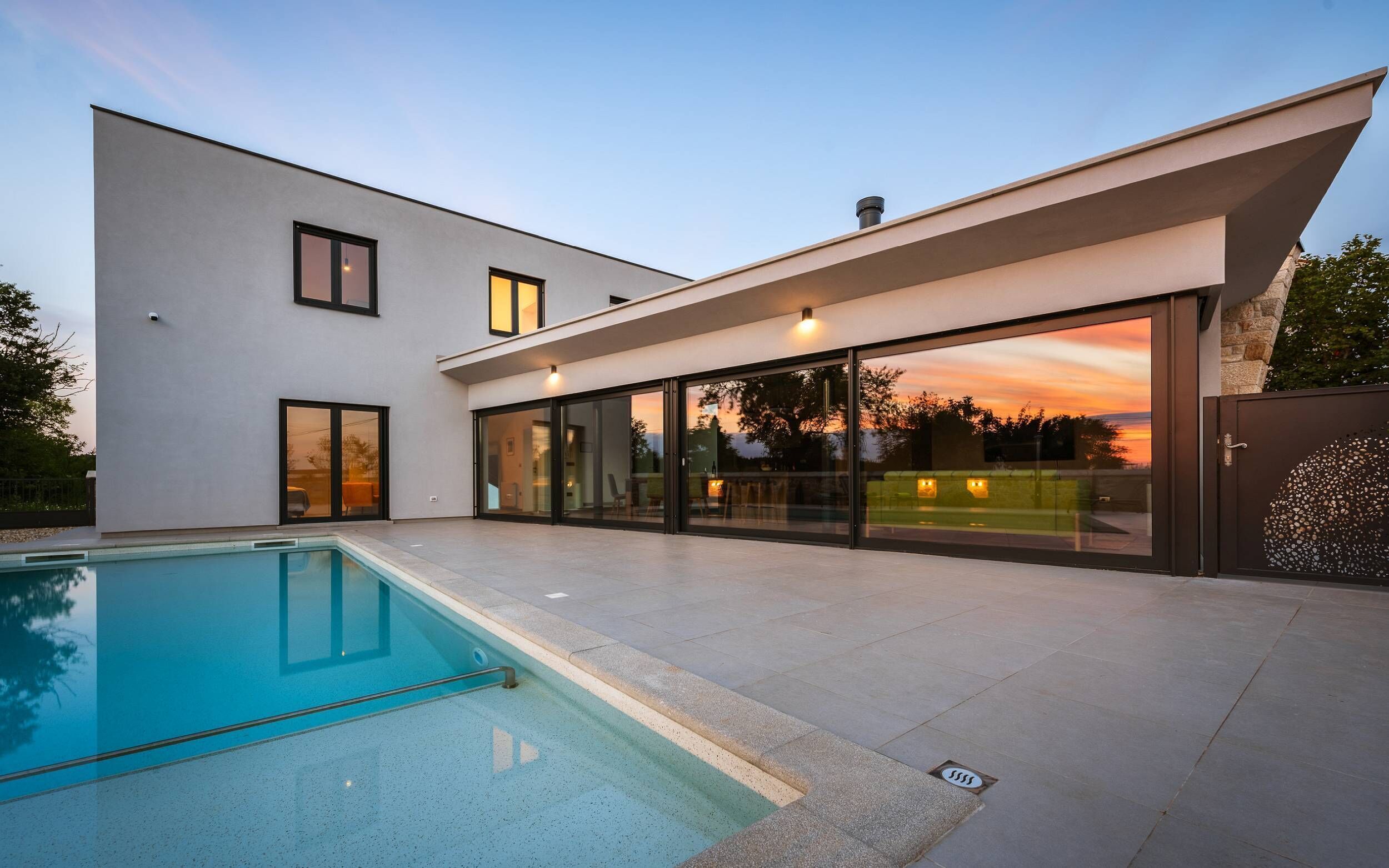 A modern house with a swimming pool, large glass doors, and a flat roof.
