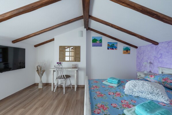 A bedroom with a wooden ceiling, a bed with floral bedding, a desk with a chair, and a TV on the wall. - Villa Country Lady (100311-K1) - Krsan (Krsan)