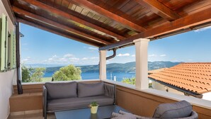 Un balcon doté d’un plafond en bois, d’un canapé gris, d’une petite table et d’une plante en pot.