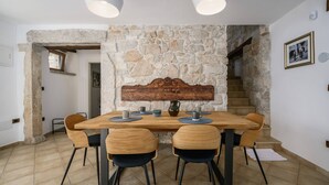 A dining area with a stone wall, wooden table, and chairs. - Villa Cangarela (100411-K1) - Visnjan (Porec) (Visnjan (Porec))