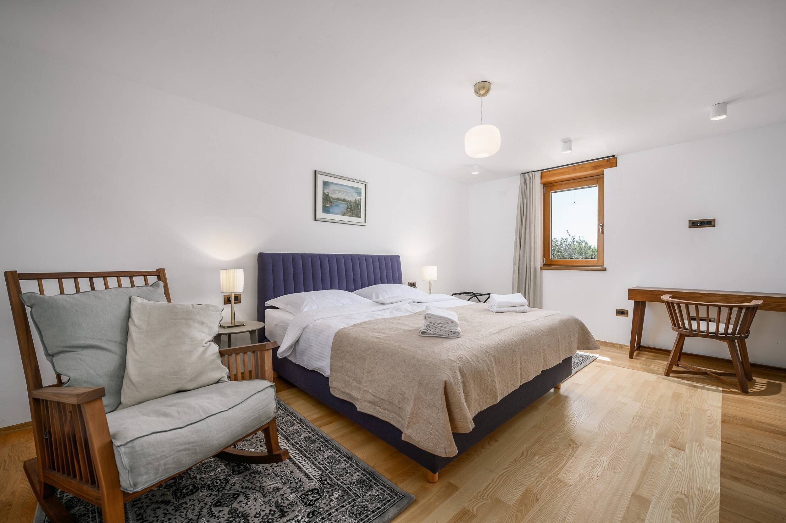 A bedroom with a bed, a desk, a chair, and a nightstand.