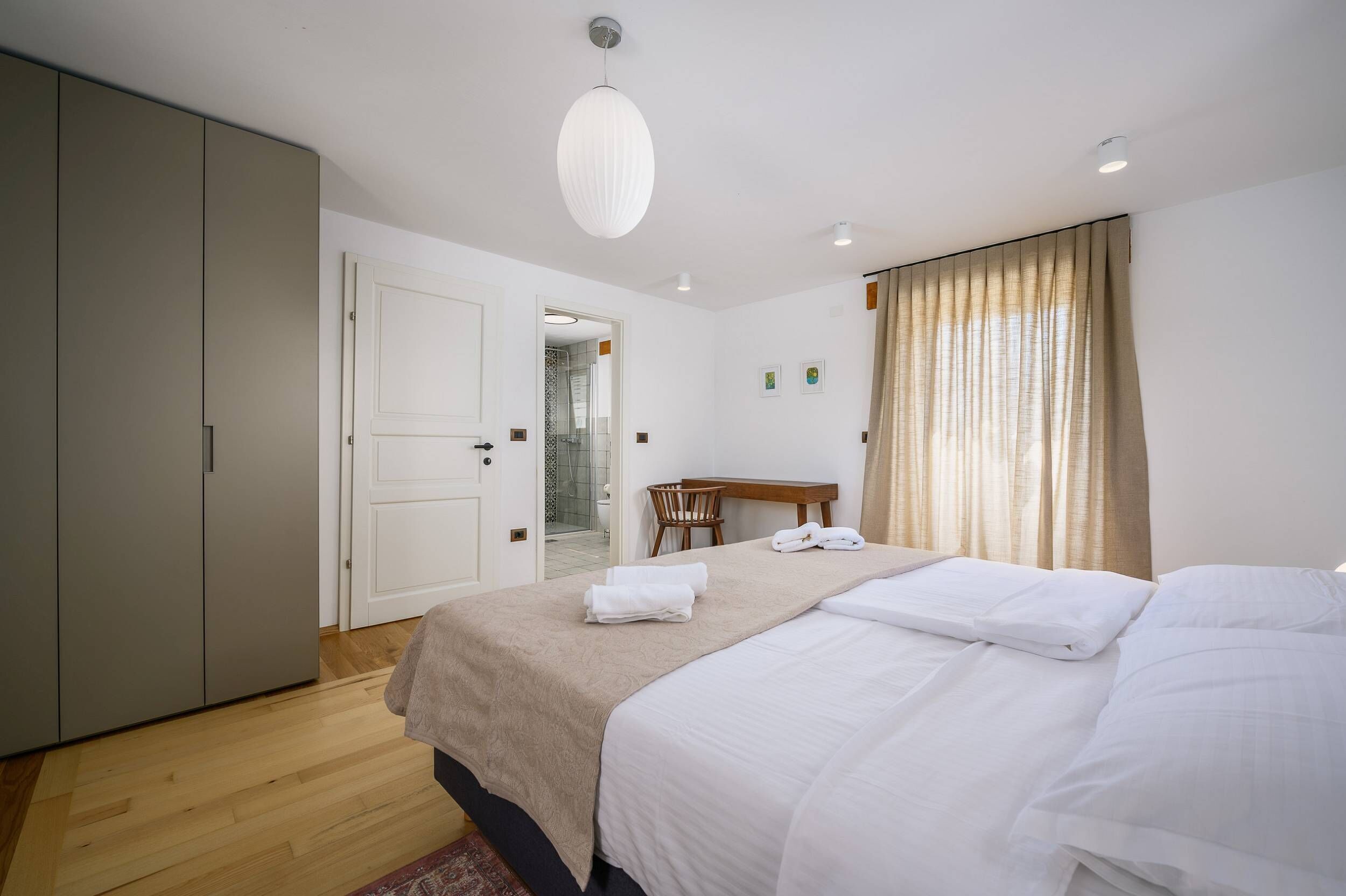 A hotel room with a bed, a desk, a chair, and a wardrobe.