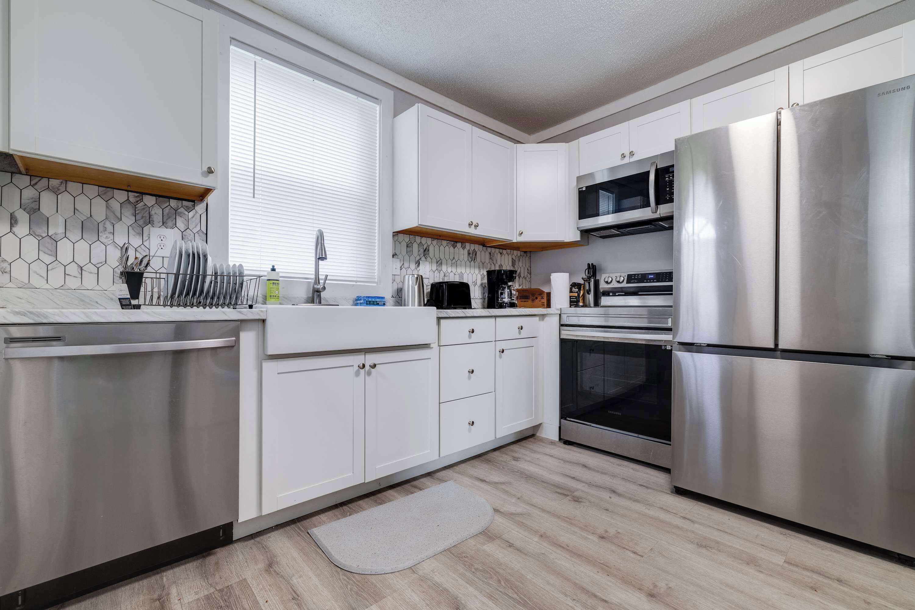 A modern kitchen with white cabinets, stainless steel appliances, a microwave, oven, and a dishwasher.