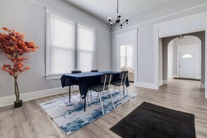 A dining area with a table, chairs, a chandelier, and a large window.