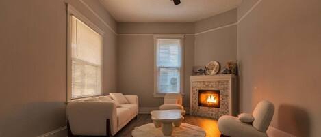 A living room with a fireplace, a ceiling fan, and a round coffee table.