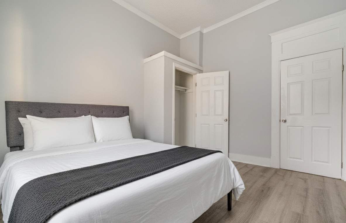 A bedroom with a bed, a wardrobe, and a door.