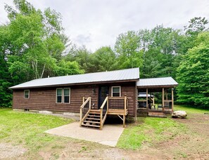 A rustic cabin with a porch, a staircase, and a small deck.