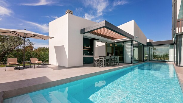 Une maison moderne dotée d’une piscine, d’un espace salon extérieur et d’une pergola.