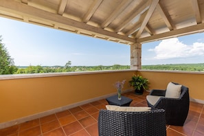 A covered balcony with wicker furniture and a potted plant. - Villa Salvea (100391-K1) - Montizana (Montizana)