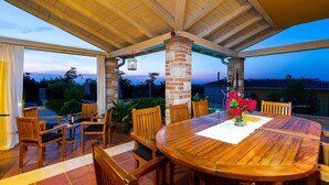 An outdoor patio with a wooden table and chairs, surrounded by brick pillars and a covered ceiling. - Villa Salvea (100391-K1) - Montizana (Montizana)