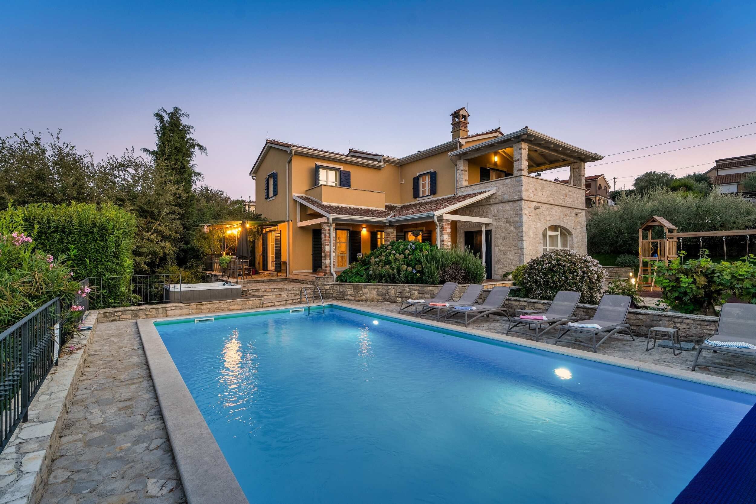A two-story house with a swimming pool, outdoor seating, and a well-maintained garden.