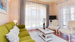 A living room with a green sofa, a white coffee table, and two white chairs. - Villa Salvea (100391-K1) - Montizana (Montizana)