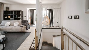 A modern living room with a sofa, a glass table, and a staircase leading to an upper level.