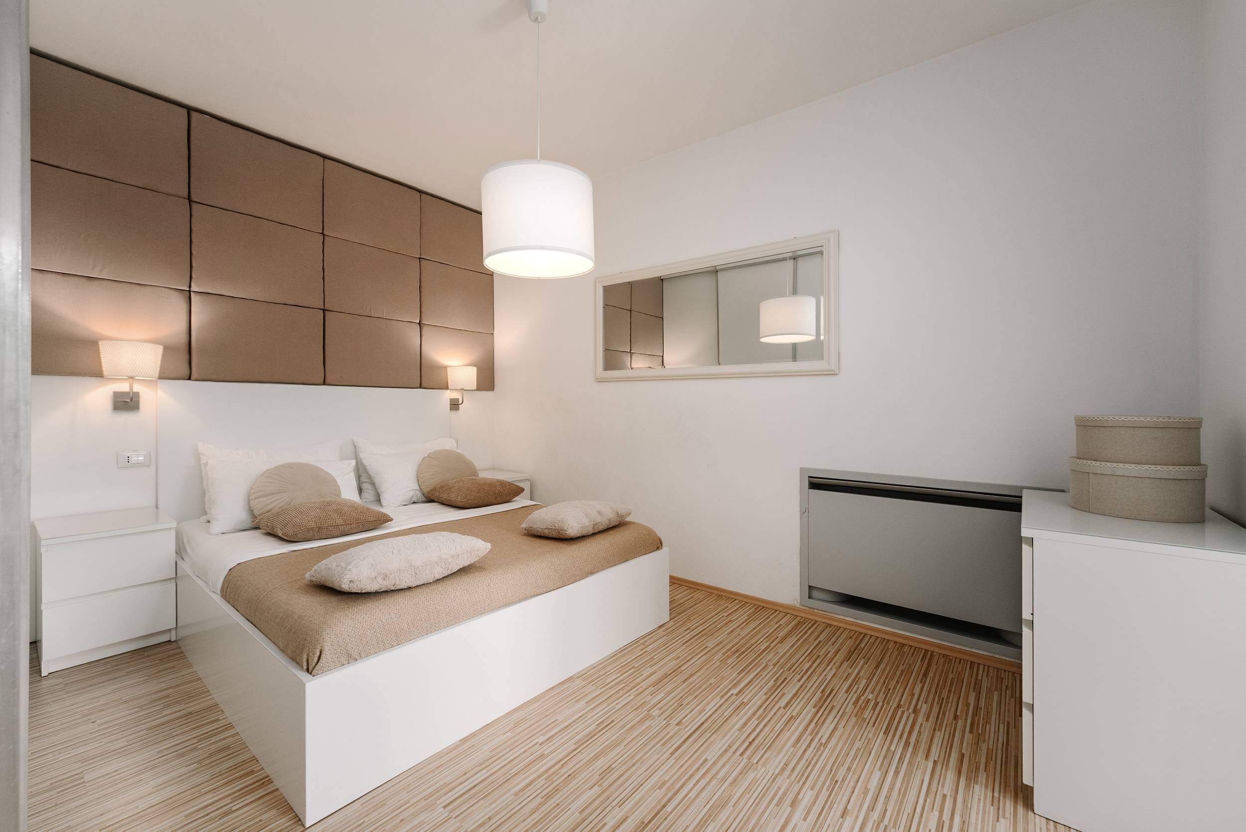 A modern bedroom with a bed, bedside lamps, a TV, and a cabinet.