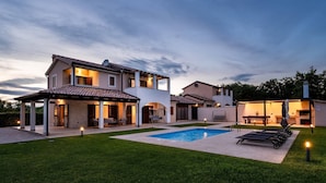A modern house with a swimming pool, outdoor seating, and a well-maintained lawn.