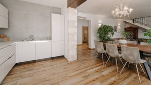 Una cucina moderna con mobili bianchi, una colonna in pietra e un tavolo da pranzo in legno con sedie.