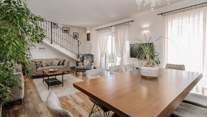 Un soggiorno moderno con un tavolo da pranzo in legno, un divano, un tavolino e una scala.