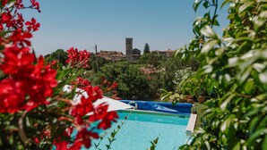 Piscina con vista su una torre storica e vegetazione circostante.