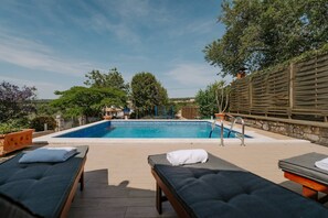 Une piscine extérieure avec des chaises longues et un mur en pierre.