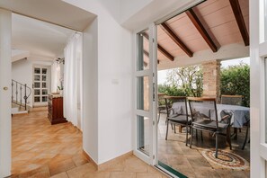 Un vaste hall d’entrée mène à un balcon doté d’un espace salon extérieur et offrant une vue sur la verdure.