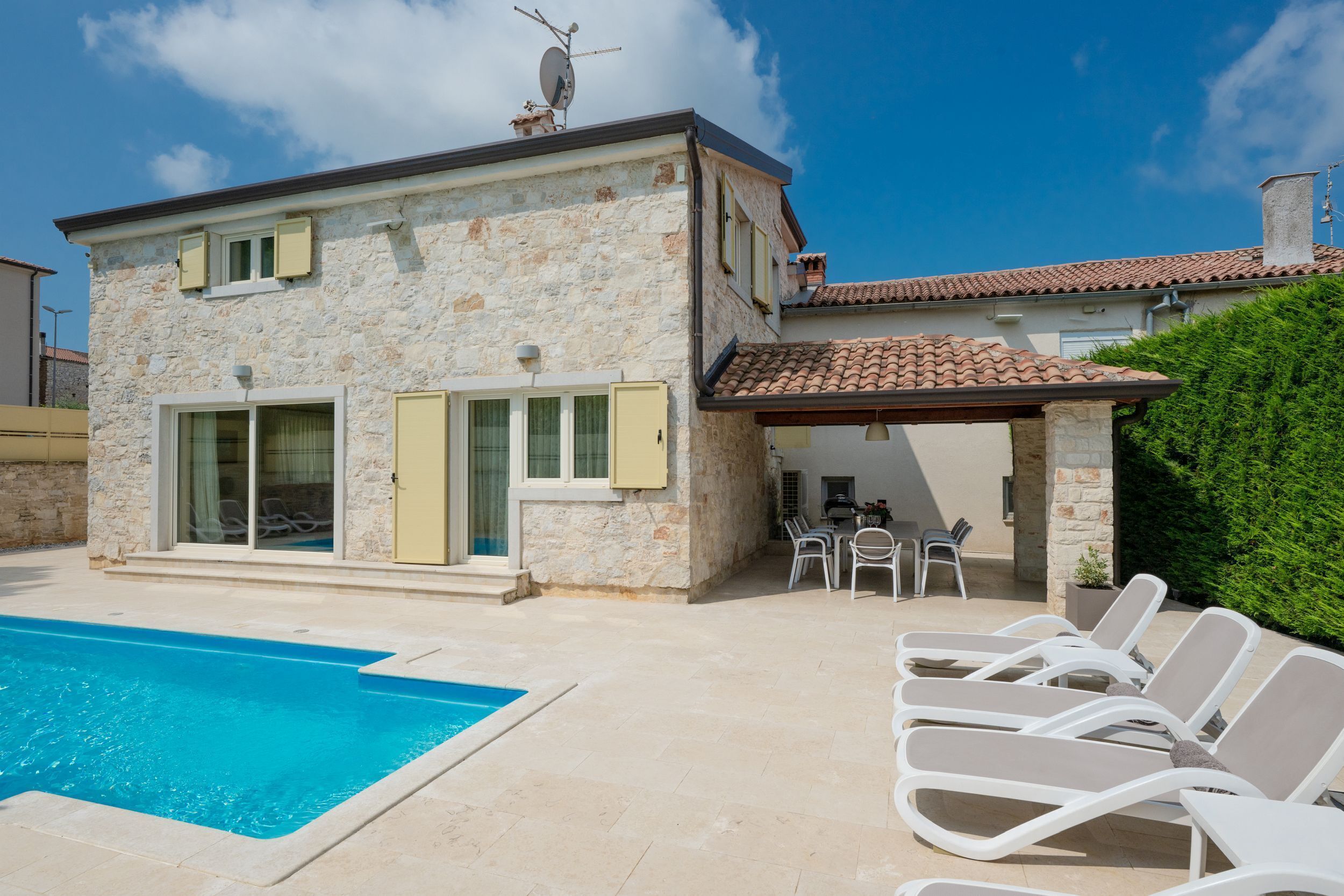 A stone house with a swimming pool and outdoor seating.
