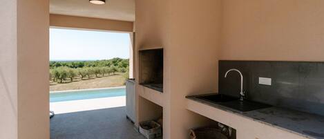 A modern kitchen with a view of a pool and vineyard.