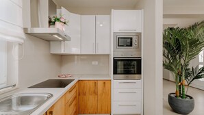 A modern kitchen with white cabinets, a wooden countertop, a stainless steel sink, a microwave, and an oven. There is a potted plant on the right. - Villa Mariella (100261-K1) - Kastelir (Kastelir)