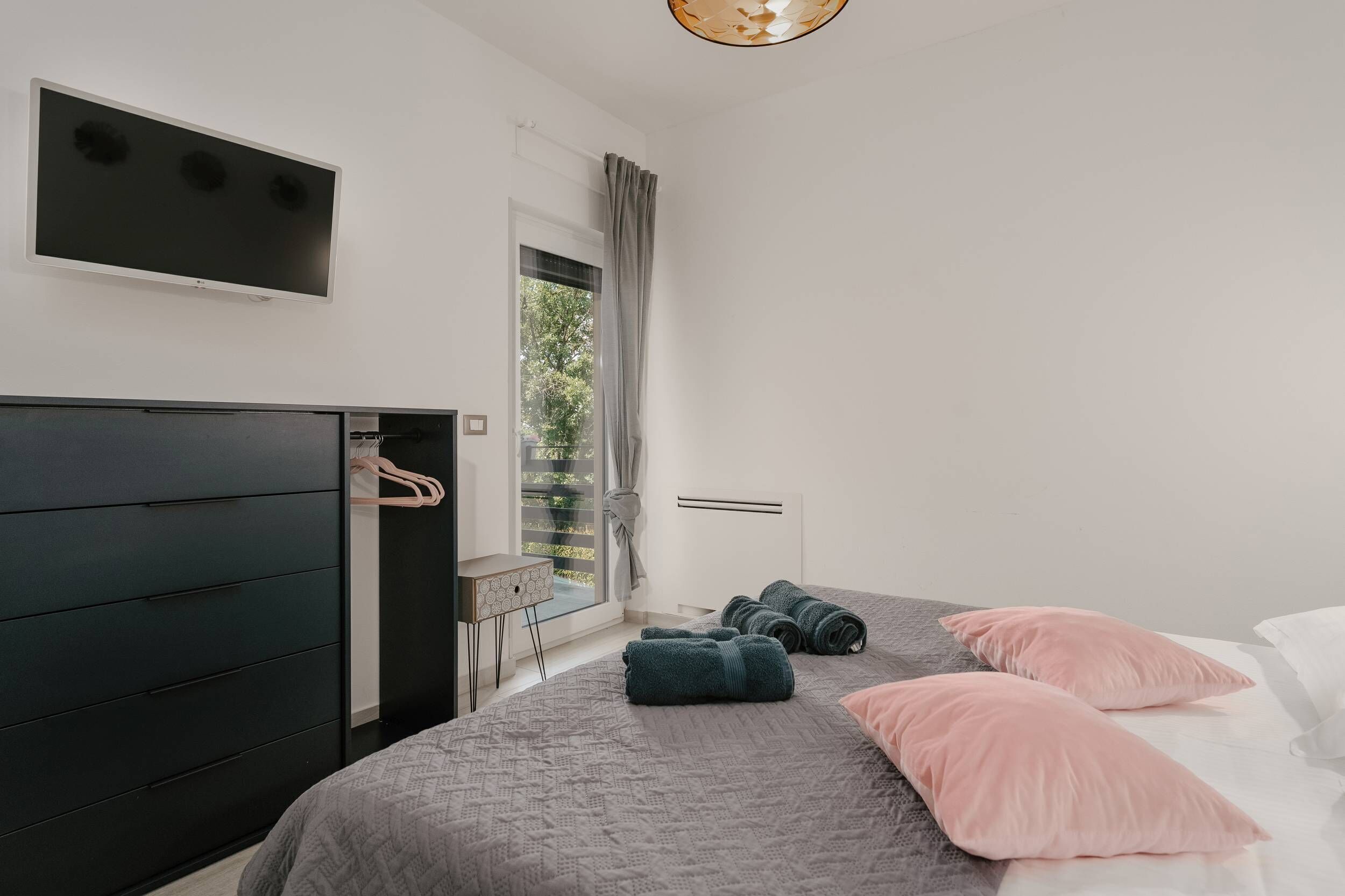 Une chambre moderne avec un lit, une armoire, un téléviseur et une fenêtre donnant sur un beau paysage.