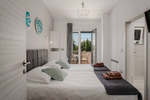Ein modernes Hotelzimmer mit zwei Betten, einem Balkon und Blick ins Grüne.