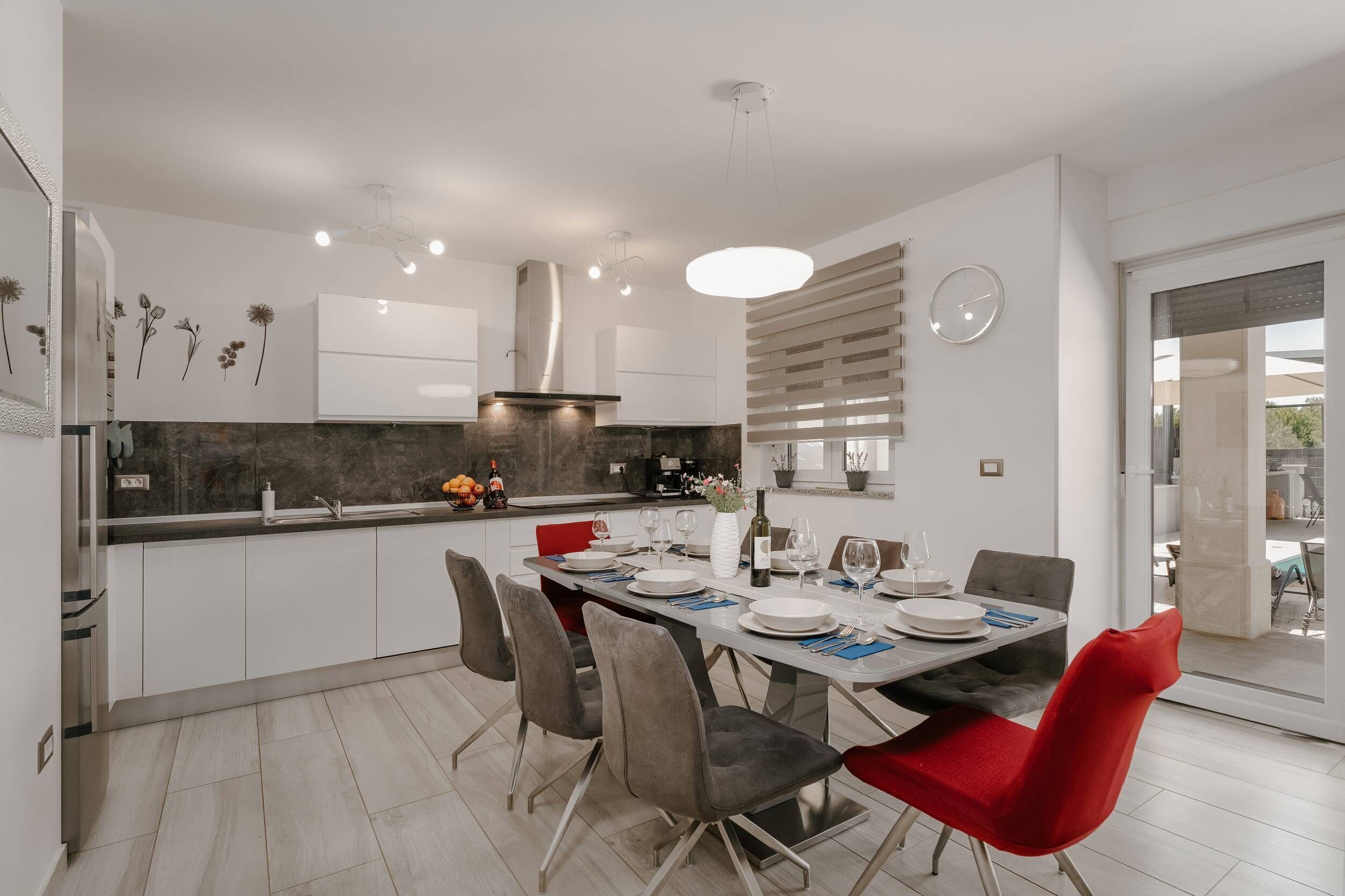 A modern kitchen with white cabinets, a central island, and a dining area with a table set for four.