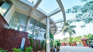 A modern building with a glass facade, a curved white structure, and potted plants. - Ocean White Sands Resort & Spa (Varca)