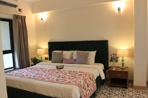 A neatly made bed with a floral bedspread, a green headboard, and two bedside lamps.